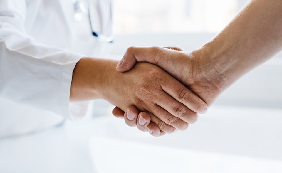 Doctor shaking hands with man in medical office