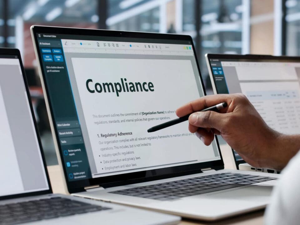 A person points at a computer screen that displays the word "compliance"